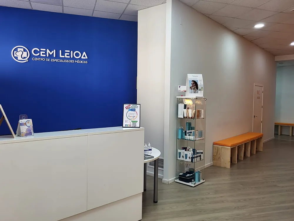 La recepción del centro: mostrador blanco delante de una pared azul con el rótulo CEM Leioa, Centro de Especialidades Médicas.